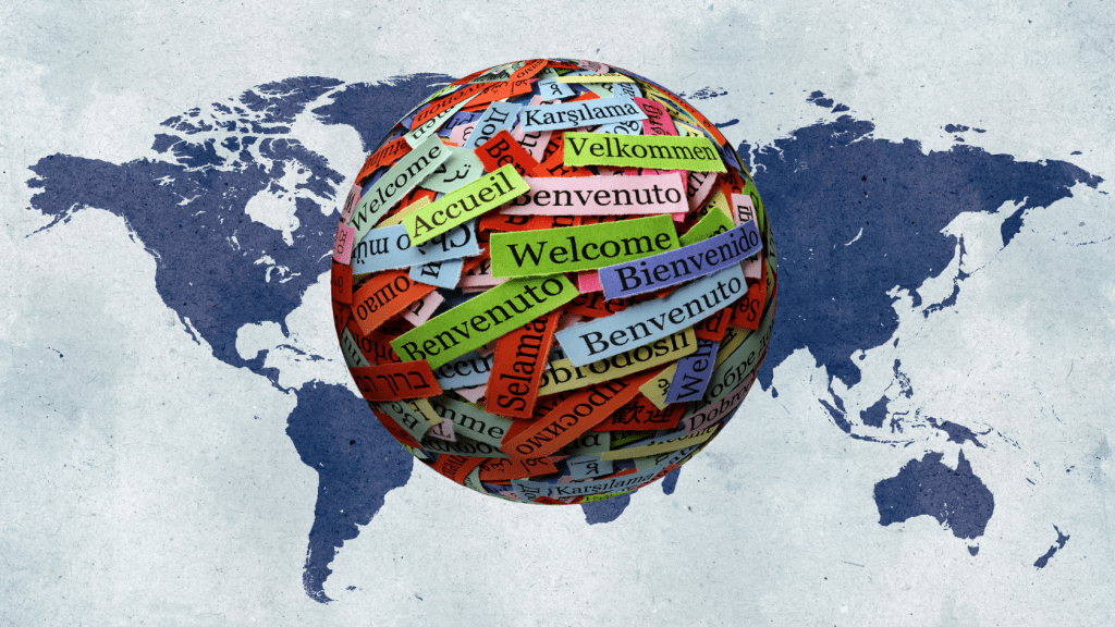 A globe covered in multilingual 'Welcome' messages in various languages, symbolizing international communication and language learning, with a world map in the background.